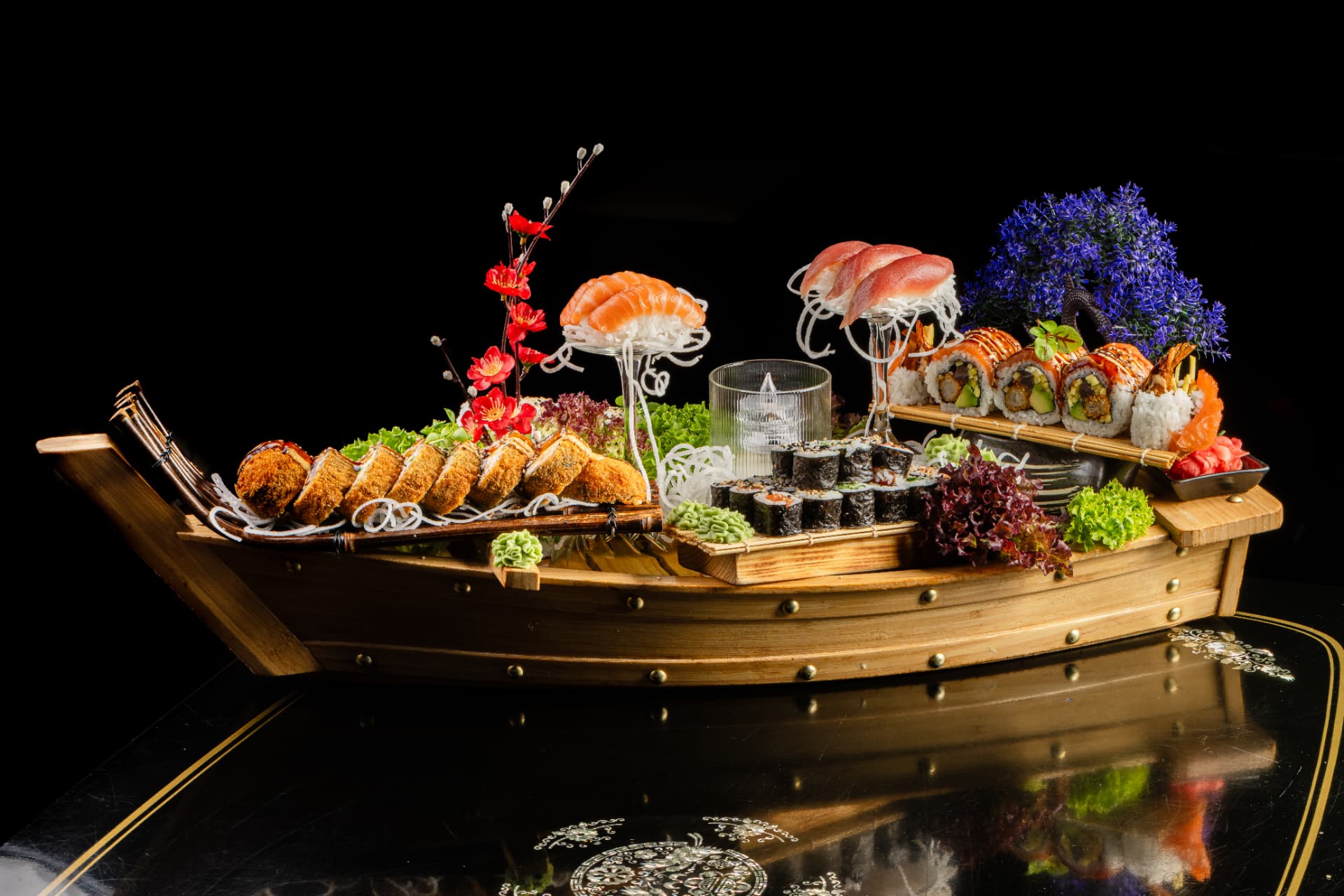 Sushi-Boot mit Nigiri, Maki und Tempura auf lackiertem Tisch